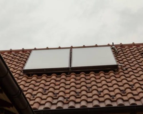 Alternative energy. Two solar collector units mounted on a roof covered with ceramic tiles