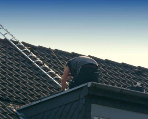 Roofer works on an unfinished roof. Installs roof shingles